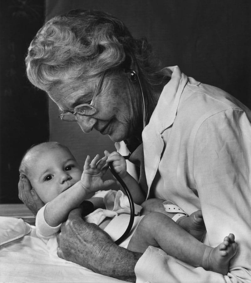 In this 1975 photo, Dr. Helen Taussig poses with a stethoscope on an infant. In real life, Taussig had little use for the instrument because of her hearing loss. (Photo by Yousuf Karsh)